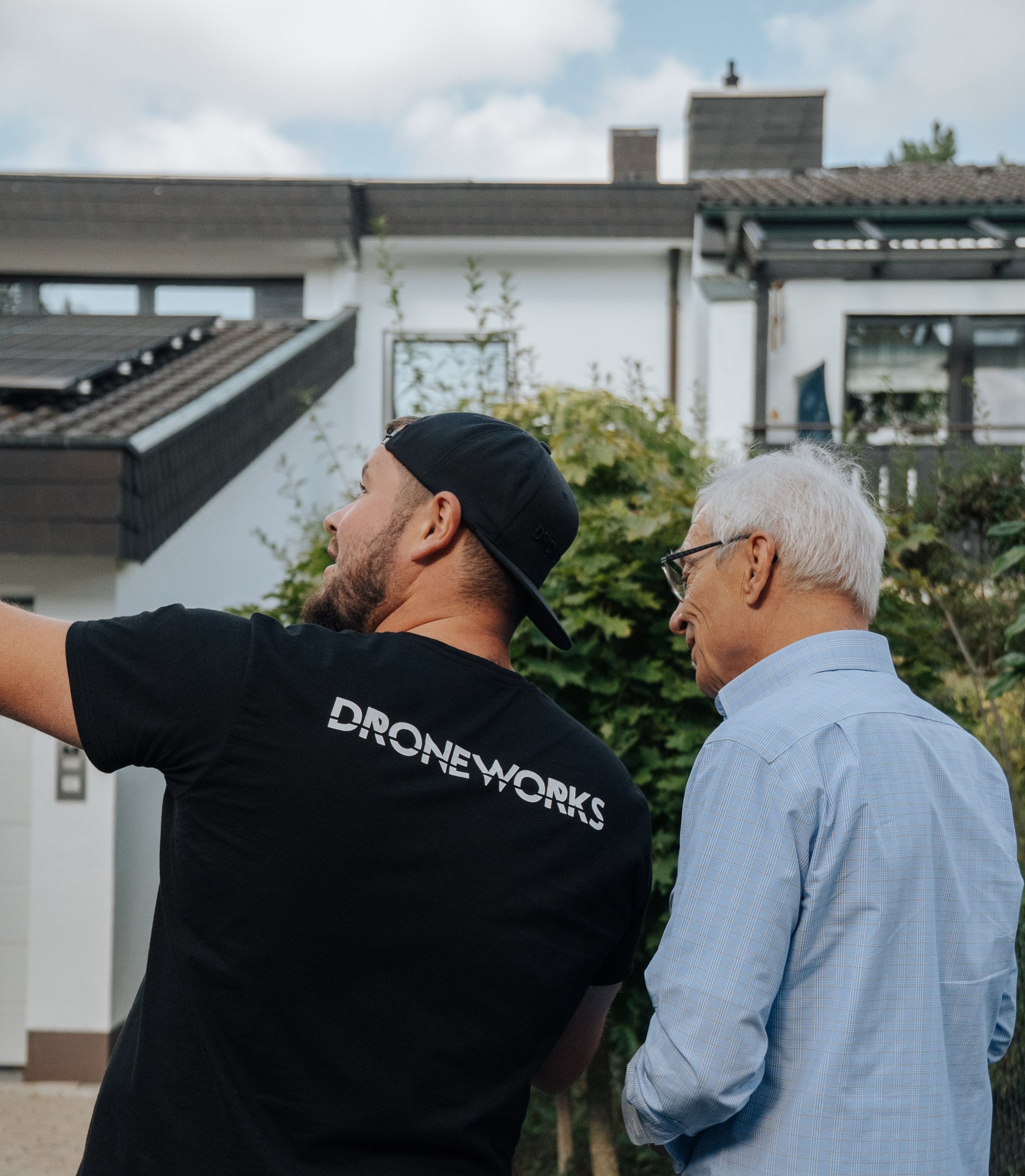 Droneworks Mitarbeiter im Kundengespräch vorm Haus, im Hintergrund die Solaranlage zu sehen.