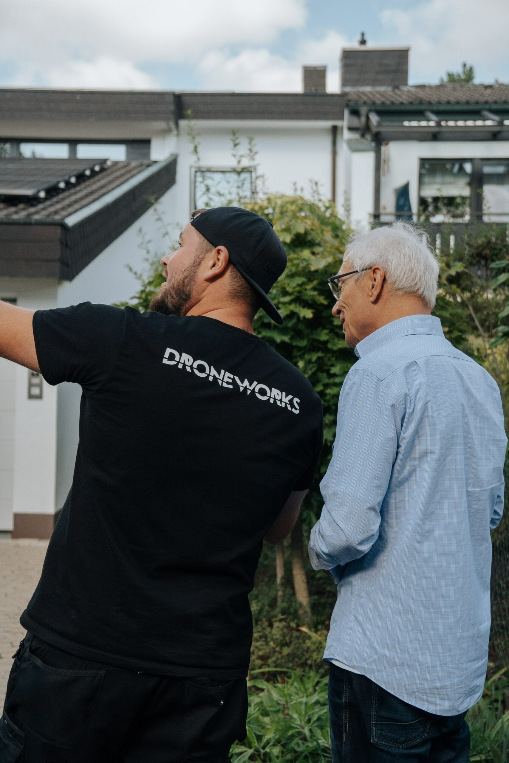 Droneworks Mitarbeiter im Kundengespräch vorm Haus, im Hintergrund die Solaranlage zu sehen.